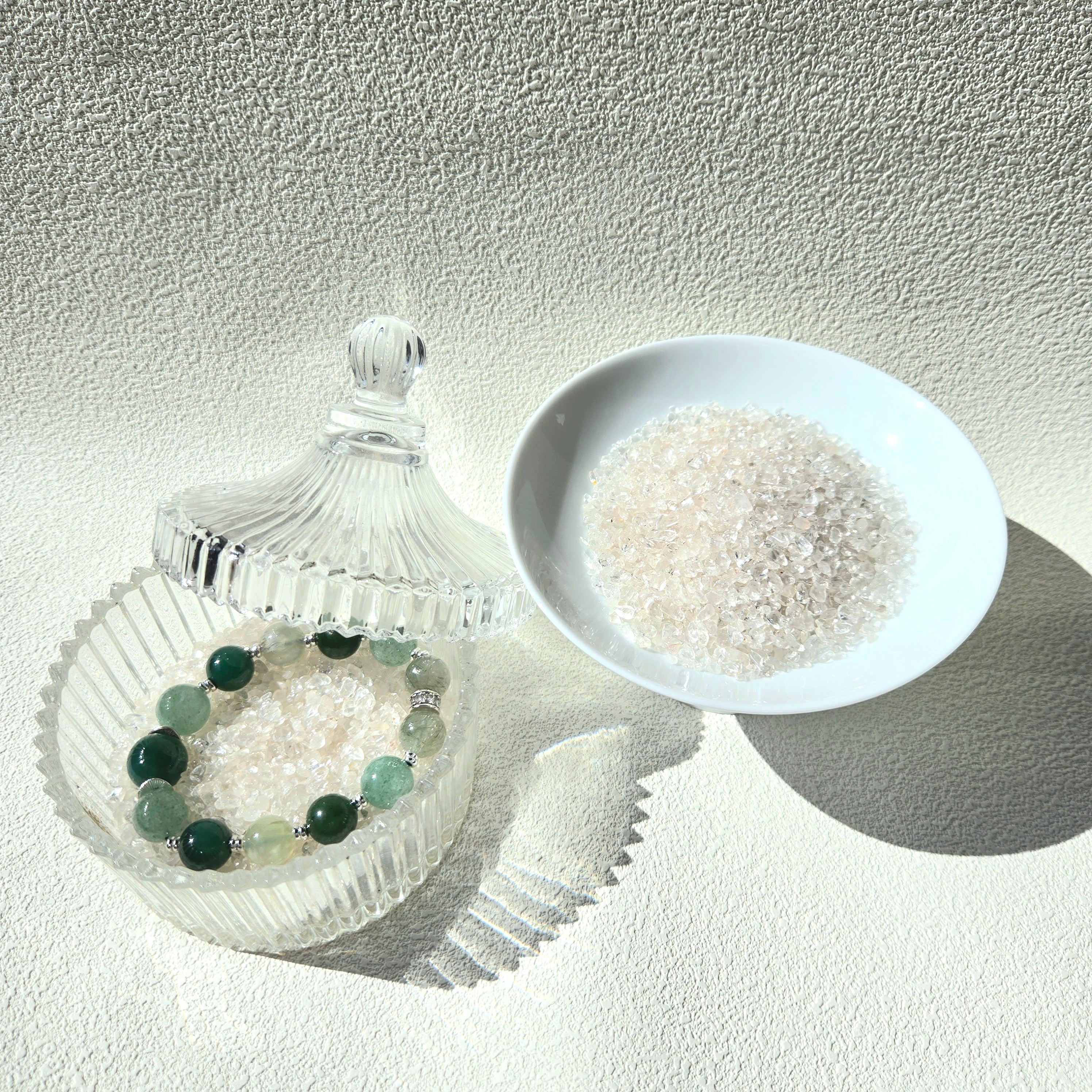 Crystal care essentials detail - bracelet resting on white quartz chips for energy purification